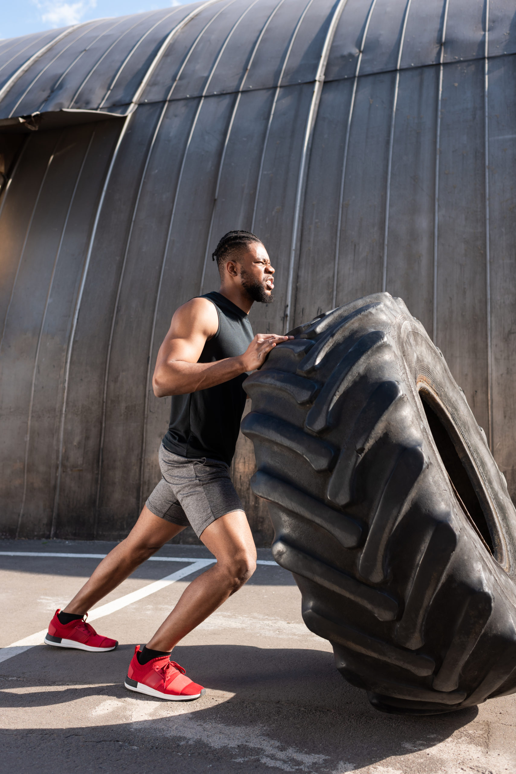 athletic african american man exercising with tire on street
